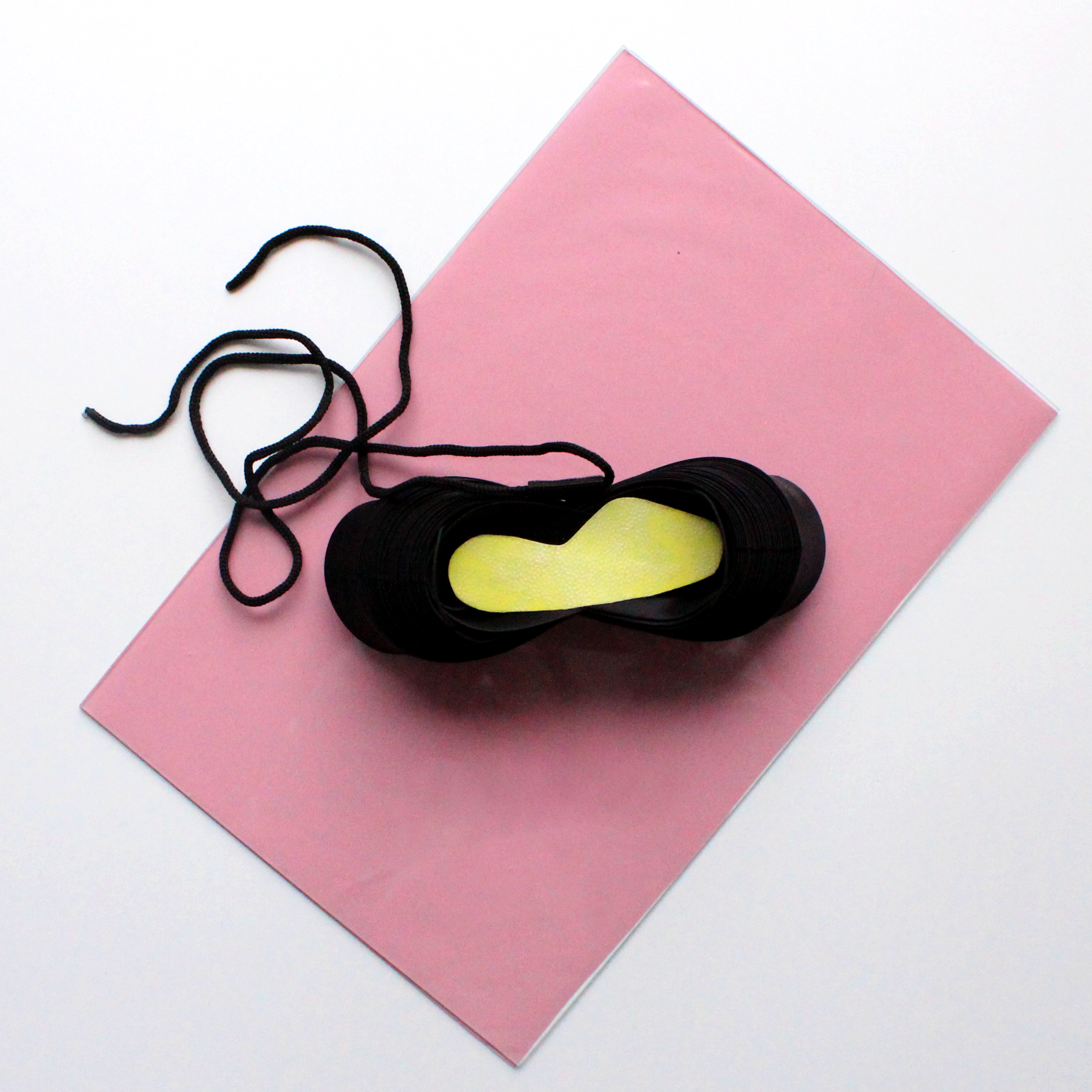 Ein schwrazer Schuh auf einem pinken Untergrund