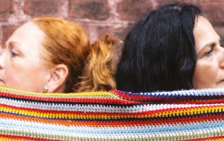 Zwei Frauen sind mit einem Wollstoff umwickelt.