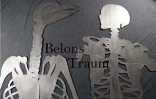 Ein menschliches Skelett und ein Skelett eines Fantasie-Wesend sehen sich an. Darüber steht "Belons Traum"