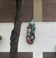 Skulptur aus von Acryl und Lack gehärteten Kleidungsstücken an einer Hauswand