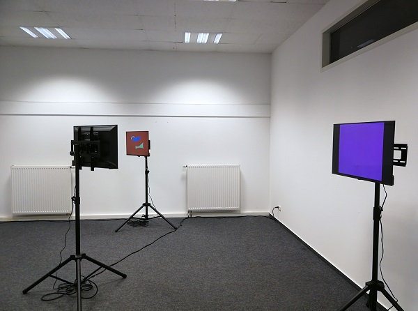 Drei Bildschirme stehen in einem Raum