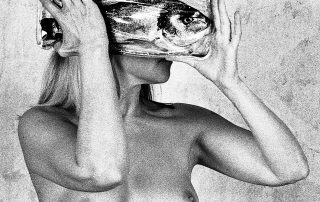 Eine nackte Frau hält ein Glas mit einem Fisch vor ihrem Kopf