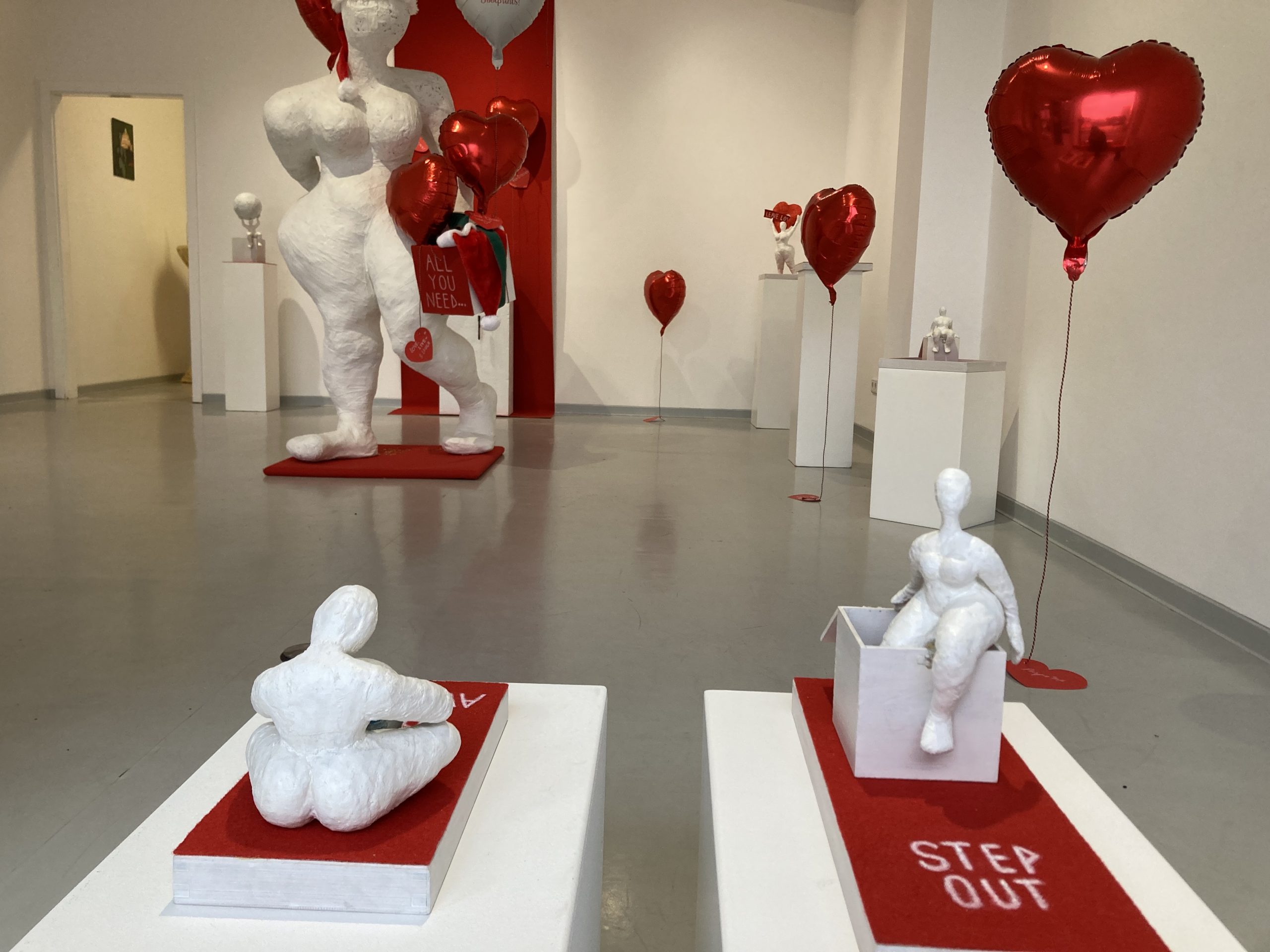 Ausstellungsraum mit mehreren Objekten und Herzluftballons dazwischen